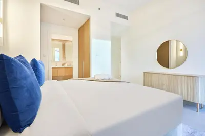 a white bed with blue pillows in a room at Modern 2BR Apartment at Grove 5 - Creek Beach & Pool Access in Dubai