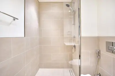a shower with a glass door in a bathroom at Modern 2BR Apartment at Grove 5 - Creek Beach & Pool Access in Dubai