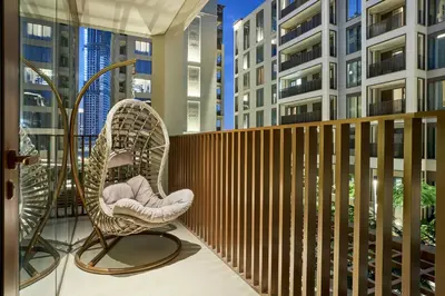 a chair on a balcony with tall buildings at Modern 2BR Apartment at Grove 5 - Creek Beach & Pool Access in Dubai