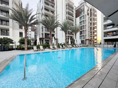 a large swimming pool with palm trees and buildings at Modern 2BR Apartment at Grove 5 - Creek Beach & Pool Access in Dubai