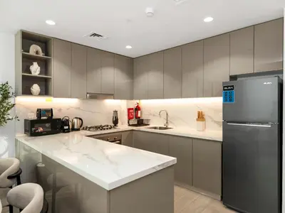 a kitchen with white counter tops and a refrigerator at Stunning 2BR at Azizi Amber Sleeps 5 in Dubai