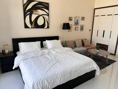 a bedroom with a large bed and a couch at Pool view Studio with balcony in Arjan in Dubai