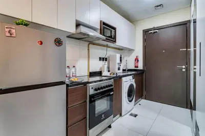 a kitchen with a stove and a washer and dryer at Studio in Liwan for long stays 1005 in Dubai