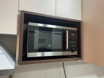 a microwave oven in a kitchen in a wall at Studio in Liwan for long stays 1005 in Dubai