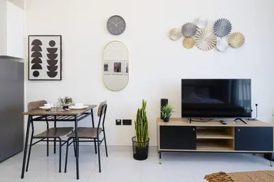 a living room with a tv and a table with chairs at New studio in Arjan ideal for long stays in Dubai