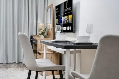 a dining room with a table and white chairs at Serene Studio at The Links Canal in Dubai