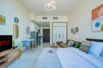 a bedroom with a large bed and a living room at Modern Studio in Barsha south with balcony in Dubai