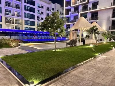 a lawn in front of a building at night at Modern Studio in Barsha south with balcony in Dubai