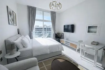 a bedroom with a bed and a desk and a tv at Skyz by Danube Studio Apartment in Arjan , Pool, Gym & Near Miracle Garden in Dubai