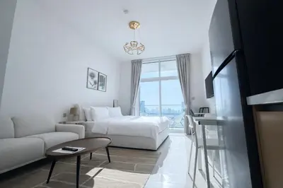 a white bedroom with a bed and a couch at Skyz by Danube Studio Apartment in Arjan , Pool, Gym & Near Miracle Garden in Dubai