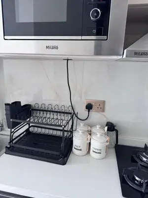 a kitchen counter with a microwave and three cups at Skyz by Danube Studio Apartment in Arjan , Pool, Gym & Near Miracle Garden in Dubai