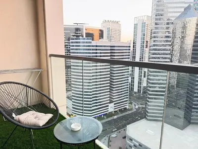 a chair and table on a balcony with a view of a city at Downtown Luxury 1BR with Pool, Gym, Fast WiFi and 8 Min Walk to Burj Khalifa in Dubai