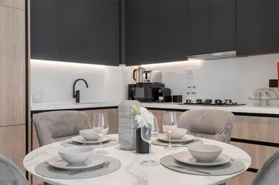 a kitchen with a table with chairs and a kitchen with black cabinets at Modern Apartment w/ Balcony & Rooftop Amenities in Dubai