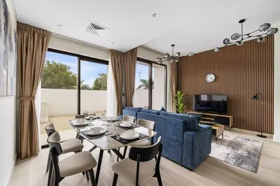 a living room with a blue couch and a table and chairs at Family Retreat 3BR Greenwoods Villa in DAMAC Hills in Dubai