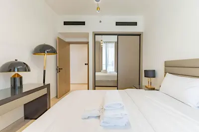 a bedroom with a large white bed with two towels at HAVN - 3 bedroom in Binghatti Crest, JVC in Dubai