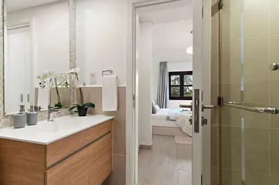 a bathroom with a sink and a shower and a bed at The Smart Concierge - Andalus Jumeirah Golf Estates in Dubai
