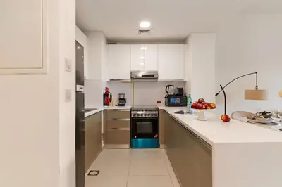 a kitchen with white cabinets and a blue oven at The Smart Concierge - Andalus Jumeirah Golf Estates in Dubai