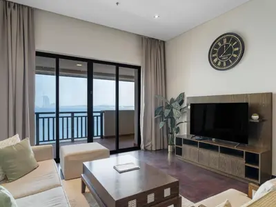 a living room with a couch and a tv at Seaside Serenity 1BR Residence in Royal Amwaj in Dubai