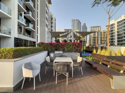 a patio with a table and chairs and a bench at Cozy 1BR with Pool & Gym l 15mn to Downtown in Dubai