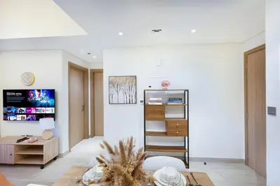 a living room with white walls and a table at Cozy 1BR with Pool & Gym l 15mn to Downtown in Dubai