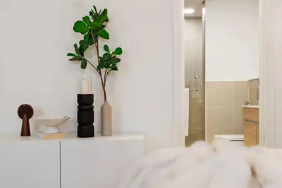 a white bathroom with a plant in a vase on a counter at The Smart Concierge - Andalus Jumeirah Golf Estates in Dubai