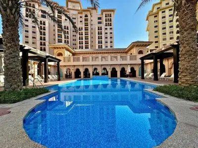 a large blue swimming pool in front of a building at The Smart Concierge - Andalus Jumeirah Golf Estates in Dubai