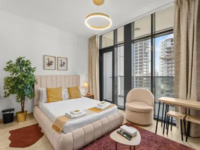 a bedroom with a bed and a large window at Warm Glow Retreat Cozy Studio In Regina JVC in Dubai