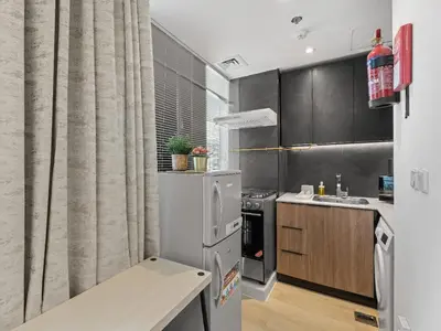 a kitchen with a refrigerator and a table in it at Warm Glow Retreat Cozy Studio In Regina JVC in Dubai