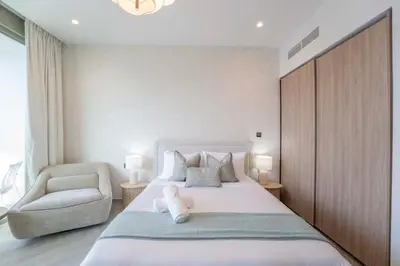 a bedroom with a large white bed and a chair at EasyGo - Chic high floor Studio with Burj View in Dubai