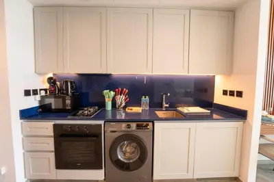 a kitchen with white cabinets and a washing machine at EasyGo - Chic high floor Studio with Burj View in Dubai