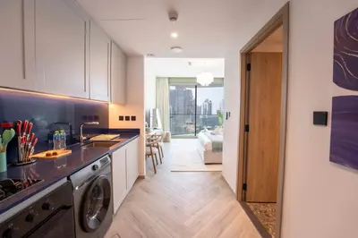 a kitchen with a washer and dryer and a living room at EasyGo - Chic high floor Studio with Burj View in Dubai