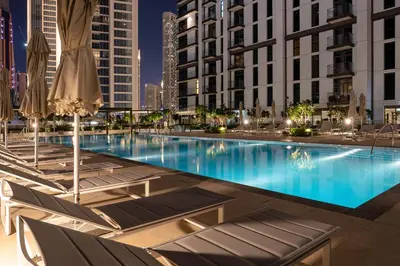 a large swimming pool with chairs and umbrellas at Downtown 4BR Apartment for 12 Guests, Burj and Dubai Mall 5 min in Dubai
