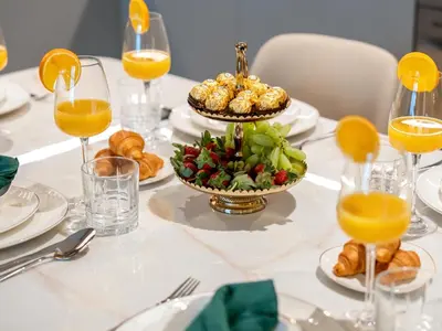 a white table with food and glasses of orange juice at Downtown 4BR Apartment for 12 Guests, Burj and Dubai Mall 5 min in Dubai
