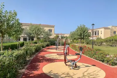 a row of exercise equipment on a path in a park at Vacationer l Serene 2 Bed Villa l Lush Garden l Family Friendly in Nadd Shubayḩ