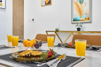 a table with a plate of fruit and orange juice at Chic 1BR at The Bay - Business Bay Near Burj Khalifa & Dubai Mall in Dubai