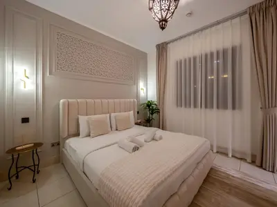 a bedroom with a large white bed with a chandelier at Luxury 2BR- Pool with Burj View- 5 Min to Dubai Mall in Dubai