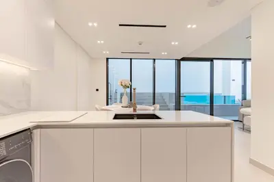 a white kitchen with a sink and a dishwasher at HAVN - 2 Bed with Private Pool, JVC in Dubai