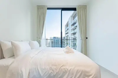 a white bed in a room with a large window at HAVN - 2 Bed with Private Pool, JVC in Dubai