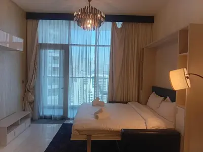 a bedroom with a bed with a chandelier and a large window at Studio Hide Away in the Business Bay in Dubai