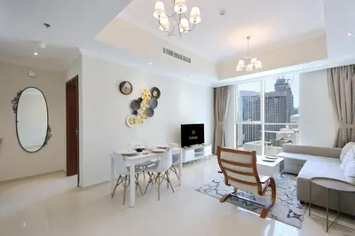 a white living room with a table and a couch at Modern 1BR next to Dubai Mall and Burj Khalifa in Dubai
