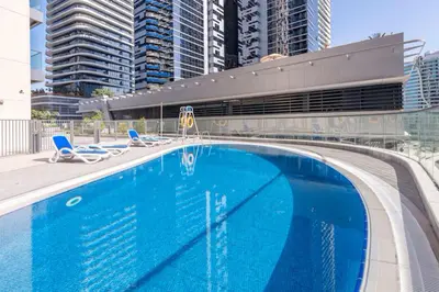 a large blue swimming pool with chairs and buildings at Modern 1BR next to Dubai Mall and Burj Khalifa in Dubai