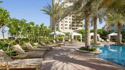 a resort with a pool with lounge chairs and palm trees at Fairmont The Palm Luxury Apt 2413 in Dubai