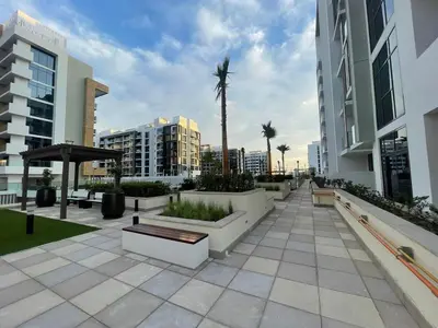 a courtyard with benches and palm trees in a city at Stylish & Luxe Studio - AZIZI 19 Riviera-Great Views in Dubai