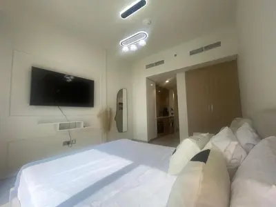 a bedroom with a large white bed and a flat screen tv at Studio in Azizi Riviera, 45 in Dubai