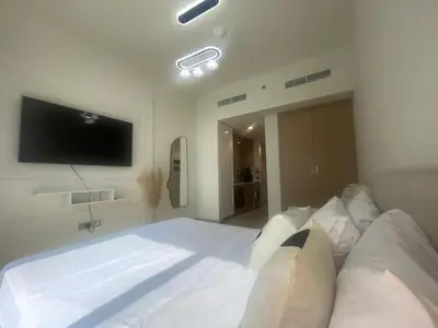 a bedroom with a large white bed and a flat screen tv at Studio in Azizi Riviera, 45 in Dubai
