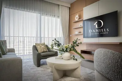 a living room with a table and chairs and a tv at Daniels 1BR in Dubai Hills with Park View in Dubai