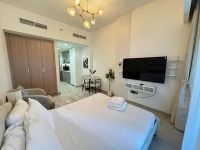 a living room with a white couch and a flat screen tv at Azizi 26 - Unique Studio for Work and Vacation in Dubai