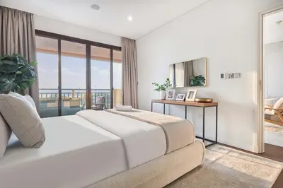 a white bedroom with a bed and a balcony at Royal Amwaj Palm Jumeirah - Luxury 1BR with Pool and Gym in Dubai