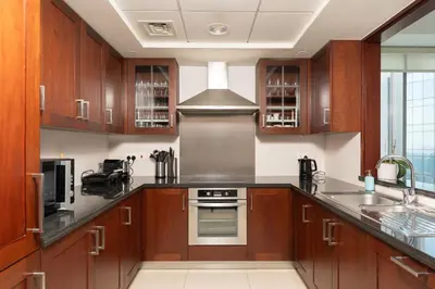 a kitchen with wooden cabinets and a stove top oven at Elegant 2BR Balcony and Stunning Burj Views in Dubai