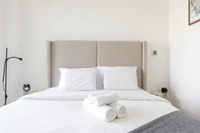 a white bed with two folded towels on it at Elegant 2BR Balcony and Stunning Burj Views in Dubai